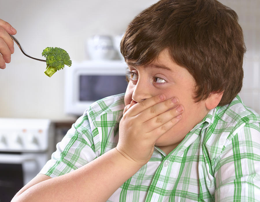 Overweight boy hates broccoli Photograph by Peter Dazeley