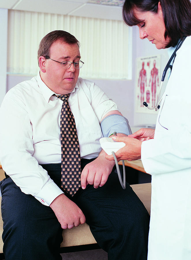 Overweight Businessman Having his Blood Pressure Taken by a Doctor Photograph by Digital Vision.