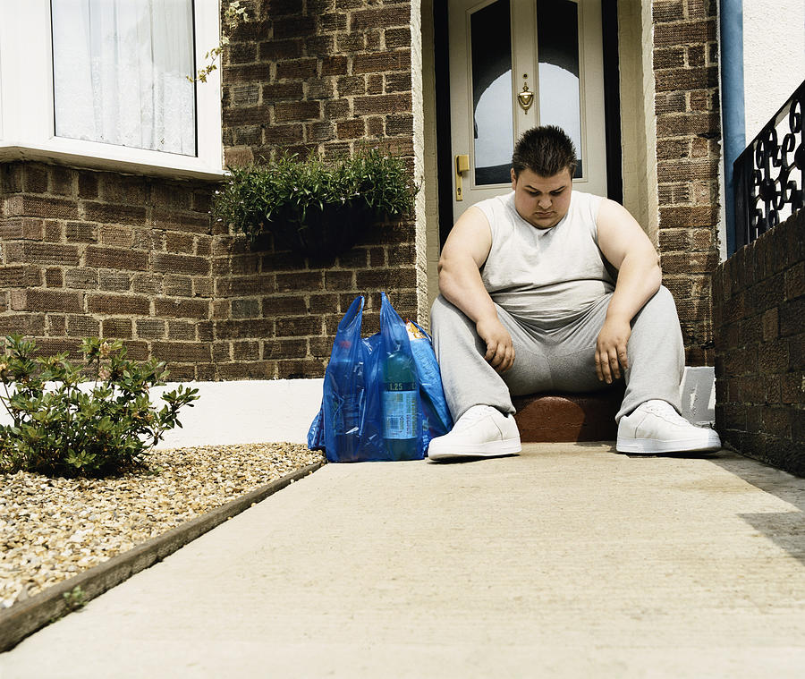 Overweight Man Sits Next to His Shopping on a Doorstep Photograph by Digital Vision.
