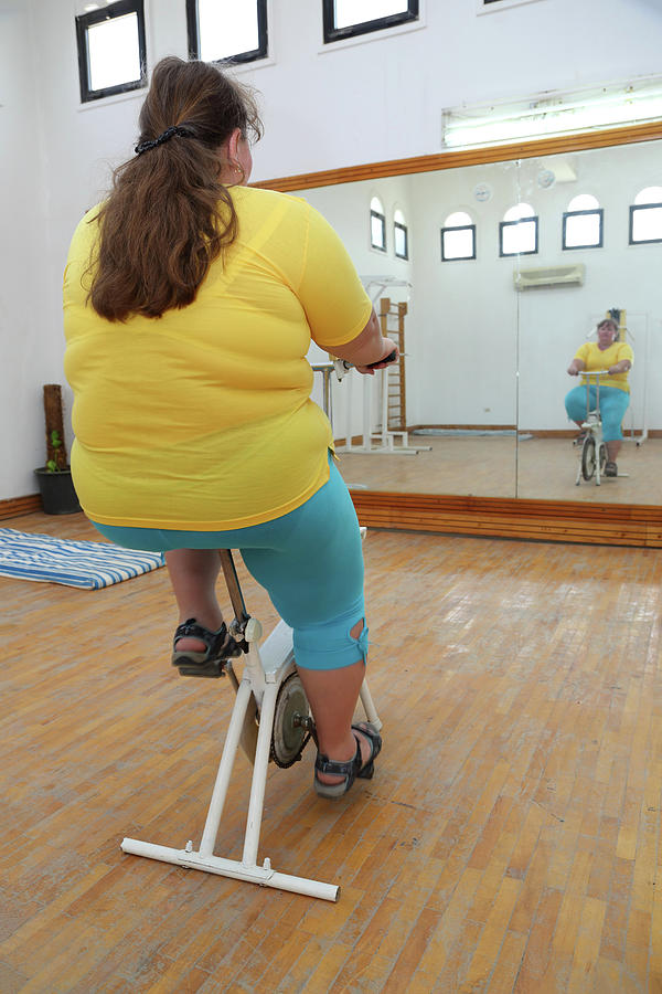 Overweight Woman Exercising On Bike Simulator Photograph by Mikhail Kokhanchikov