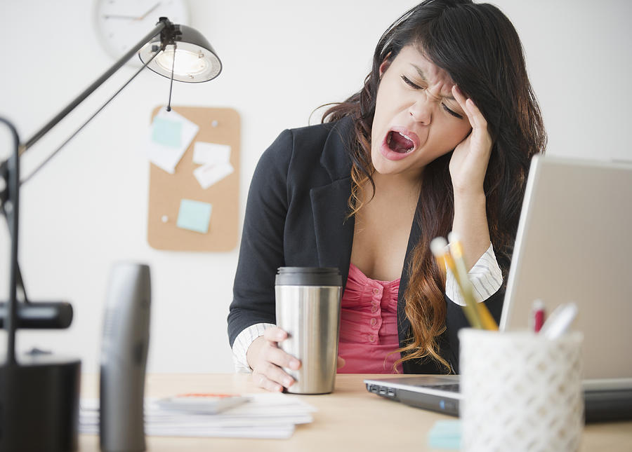 Pacific Islander businesswoman yawning at desk Photograph by JGI/Jamie Grill