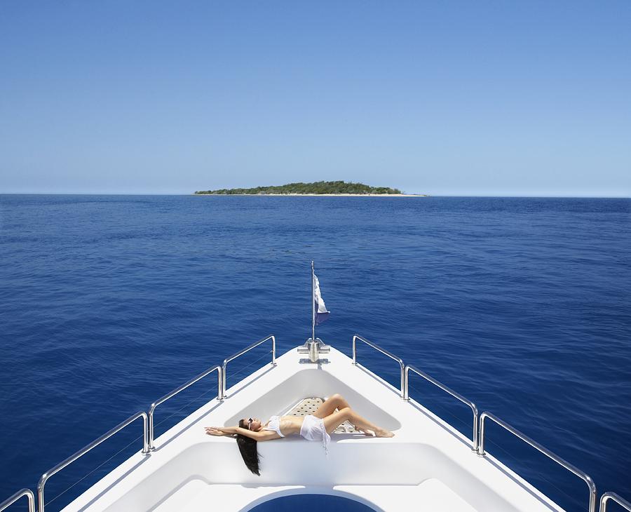 Pacific Islander woman sunbathing on bow of yacht Photograph by Colin Anderson Productions pty ltd