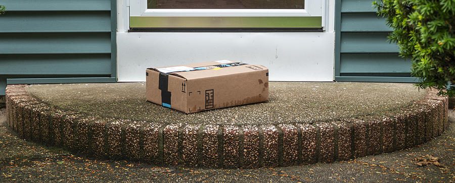 Package left out in the rain exposed on a front porch Photograph by WoodysPhotos