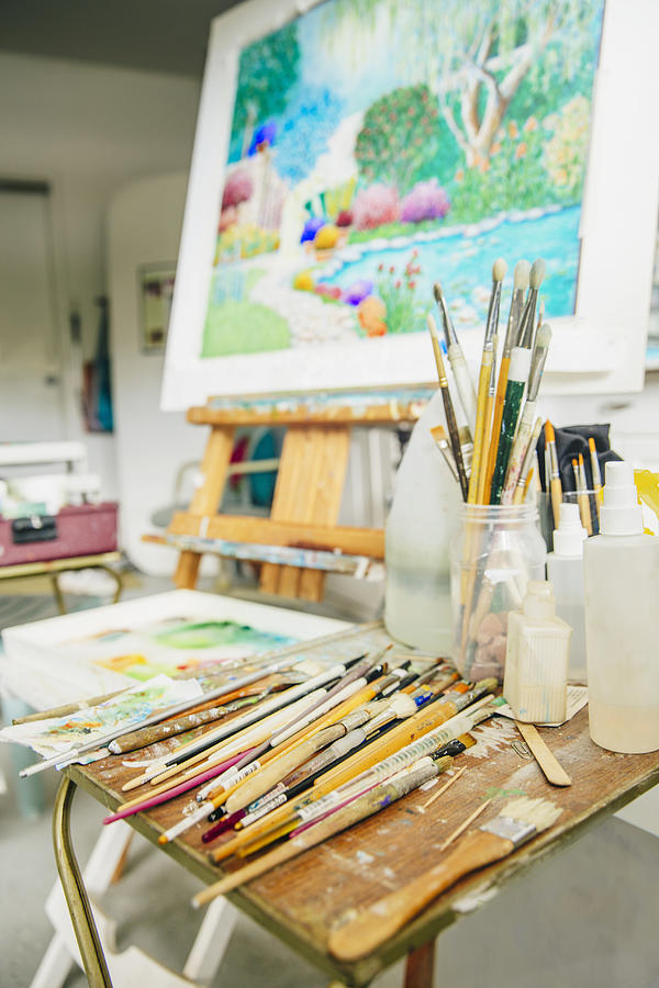 Paintbrushes, palette and easel with painting in studio Photograph by Inti St Clair