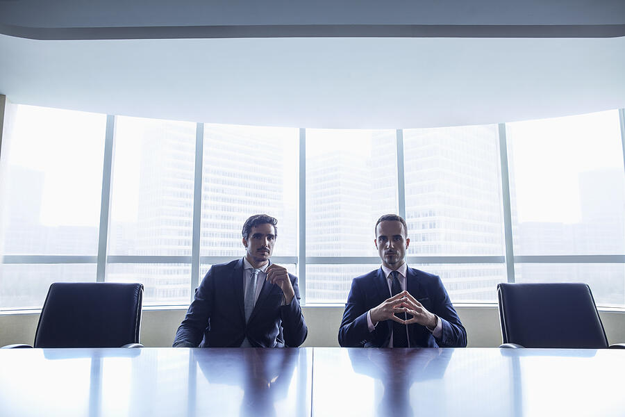Pair of businessmen sitting at conference table Photograph by Shannon Fagan