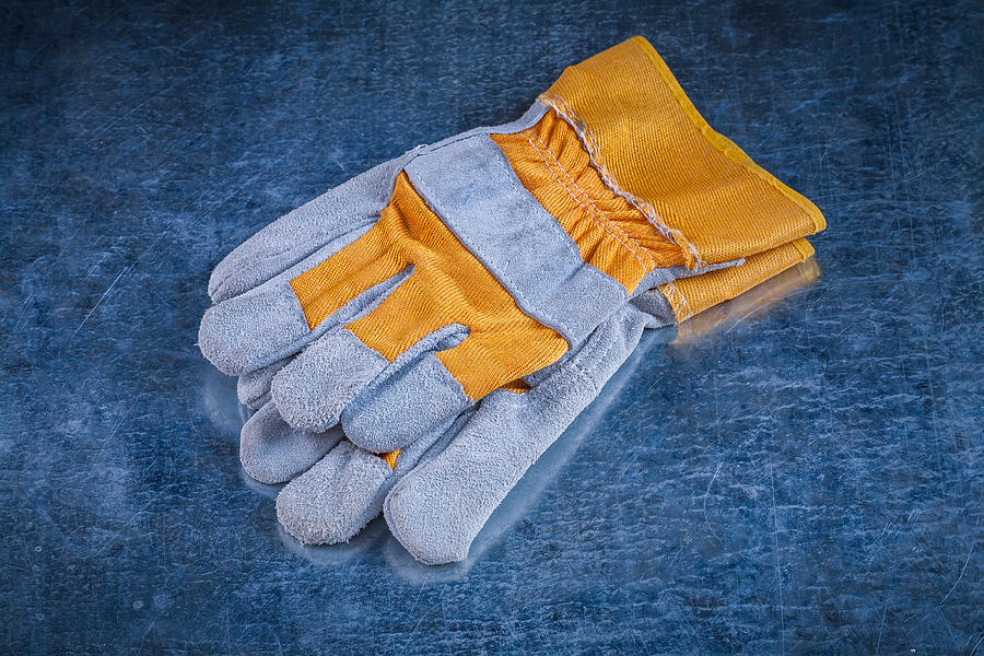 Pair of safety working gloves on scratched vintage metallic back Photograph by Mihalec