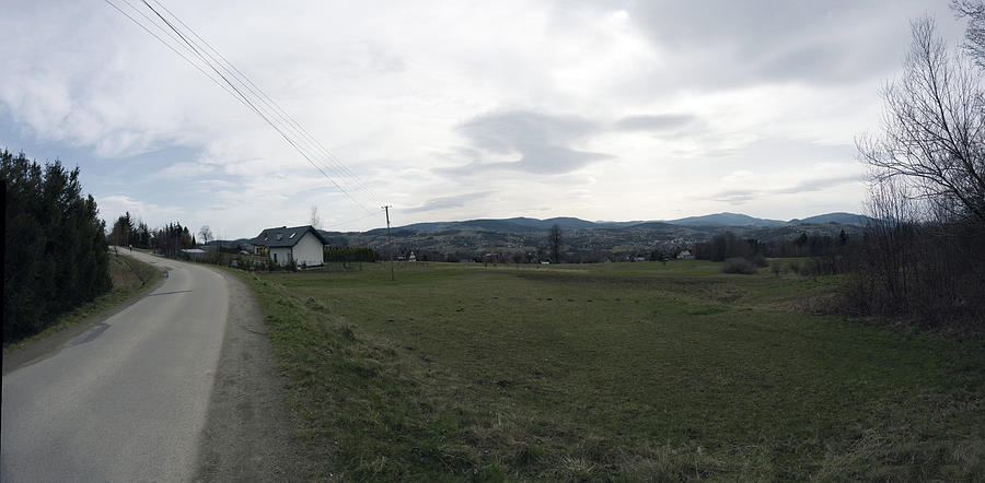 Panorama shot of a Country road bending or turning showing beautiful landscape along with a wooden farm house. Tymbark village located in Limanowa, South Poland. Photograph by Arpan Bhatia