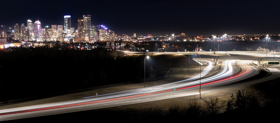 Panoramic night cityscape of Calgary with lightrails Photograph by Peter Kolejak
