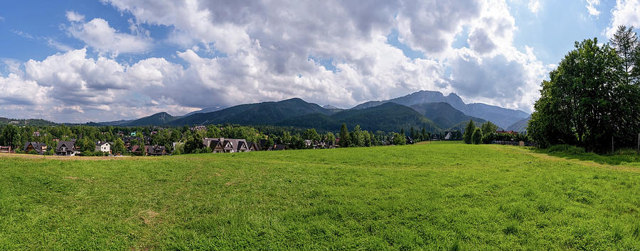 Panoramic view of green grass meadow countryside field with A shaped houses against sleeping knight tatra mountain aka as giewont and dramatic clouds located in Zakopane, South Poland, Europe Photograph by Arpan Bhatia