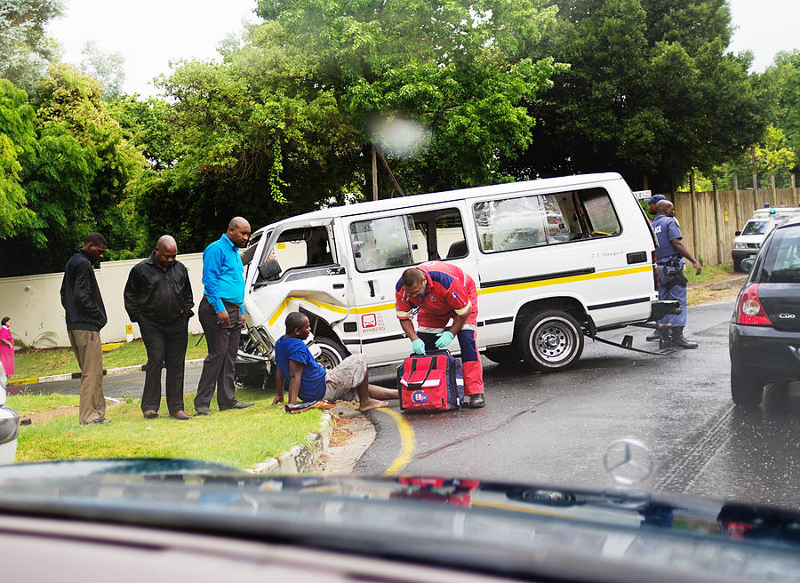 Paramedic attending injured passenger after minibus taxi accident Photograph by RapidEye