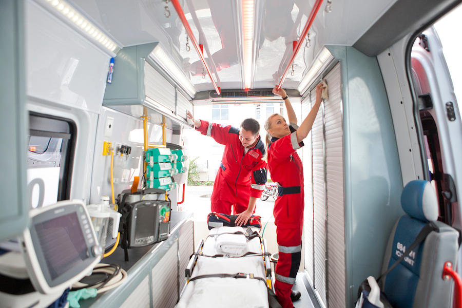 Paramedics in ambulance preparing medical equipment Photograph by Zero Creatives