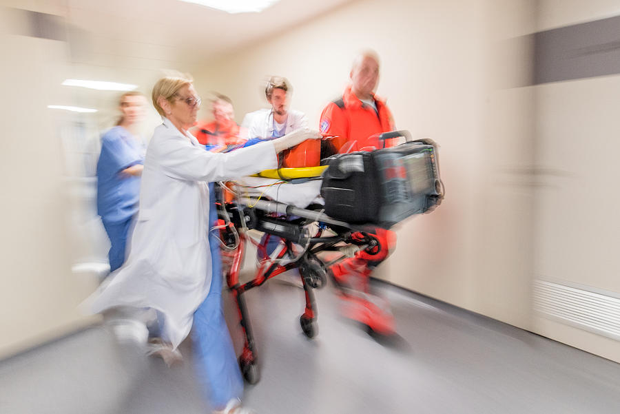 Paramedics wheeling patient in hospital Photograph by Simonkr