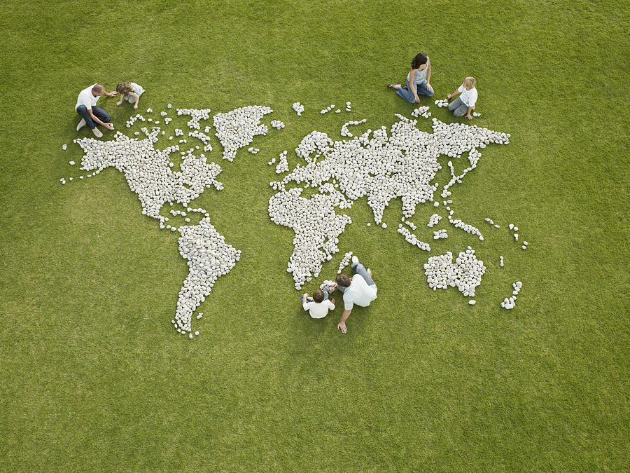 Parents and children making world map made of rocks Photograph by Martin Barraud