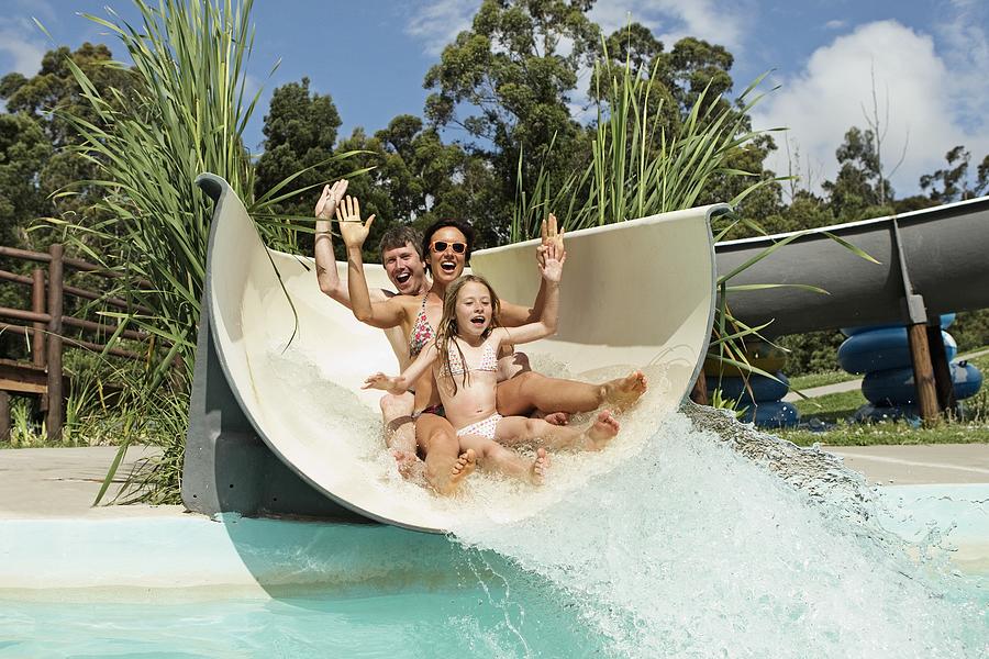 Parents with daughter (6-7) going down water slide Photograph by Tomas Rodriguez/Corbis