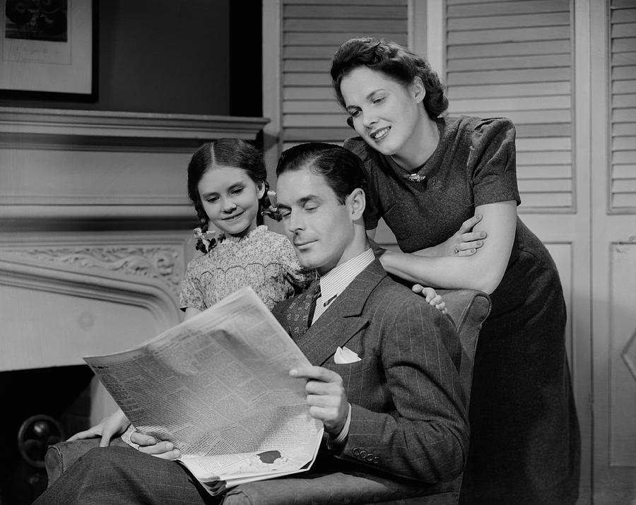 Parents with daughter (6-7 years) reading newspaper together Photograph by George Marks