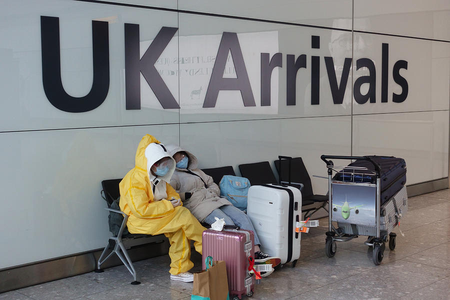 Passengers arriving in UK wearing protective clothing Photograph by Peter Cade