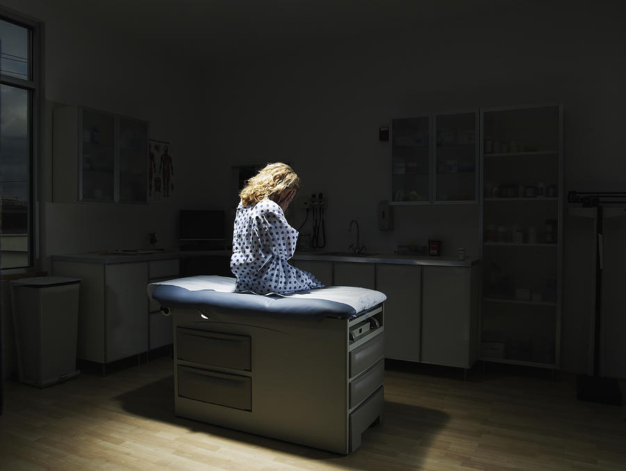 Patient sitting on examination table, rear view Photograph by Thomas Barwick