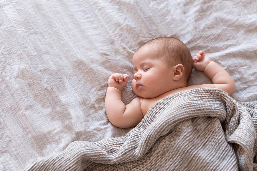 Peaceful baby lying on a bed and sleeping at home Photograph by Amax Photo