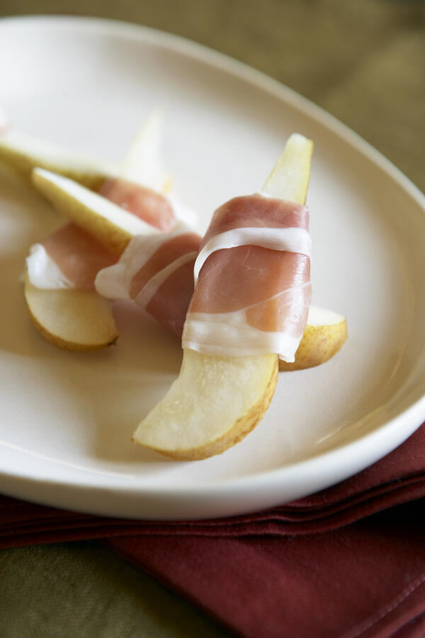 Pears wrapped in proscuitto in plate, close-up, elevated view Photograph by Maren Caruso