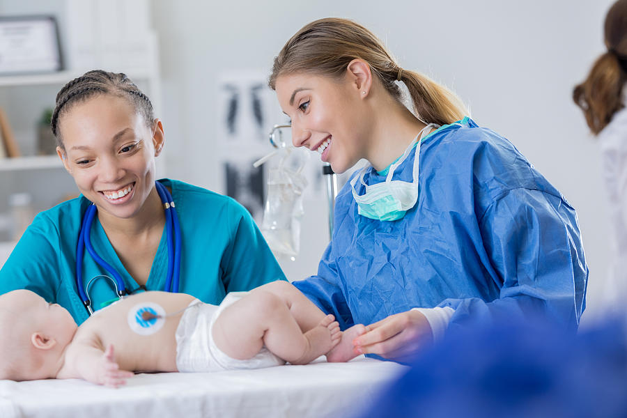 Pediatric surgeon examines infant Photograph by SDI Productions