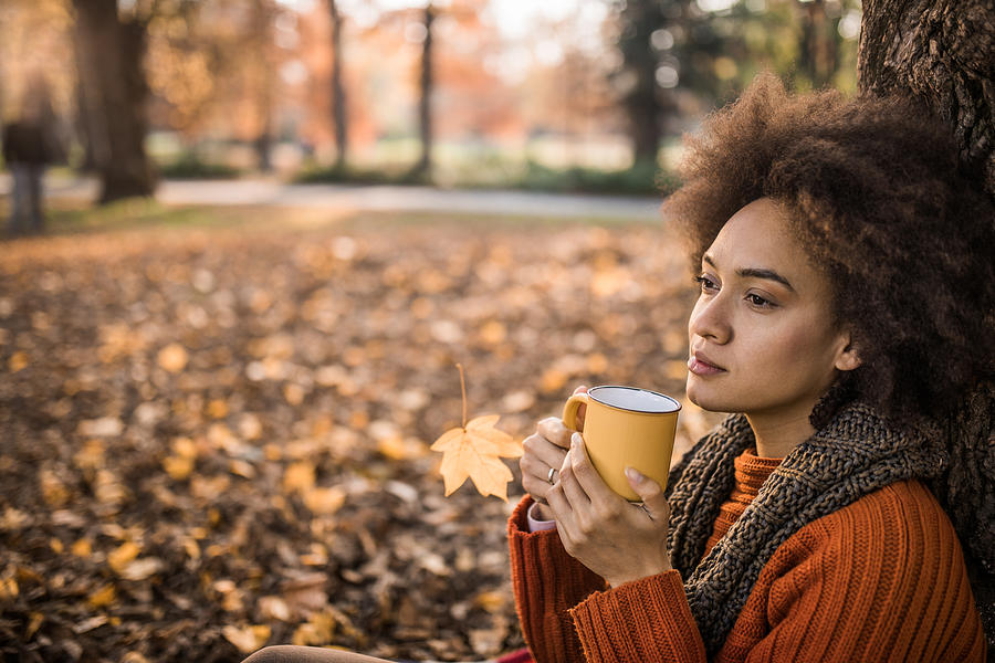 Pensive African American woman drinking tea during autumn day in nature. Photograph by Skynesher
