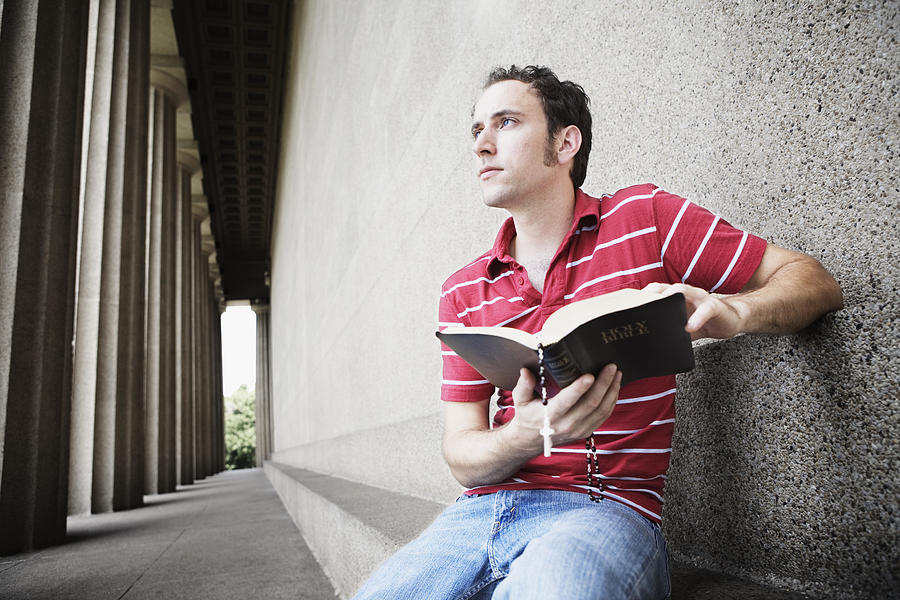 Pensive man holding open bible Photograph by Jupiterimages