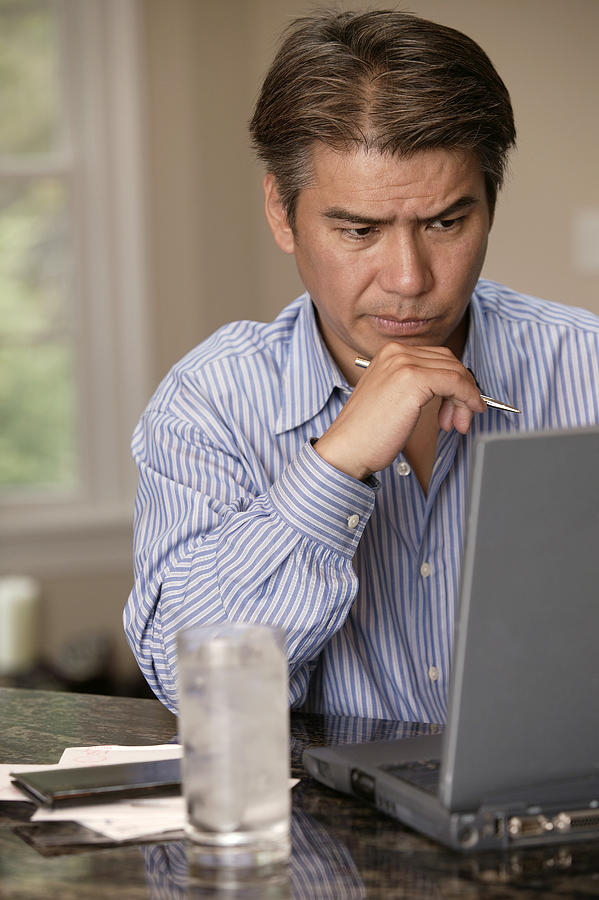 Pensive man using laptop Photograph by Comstock Images