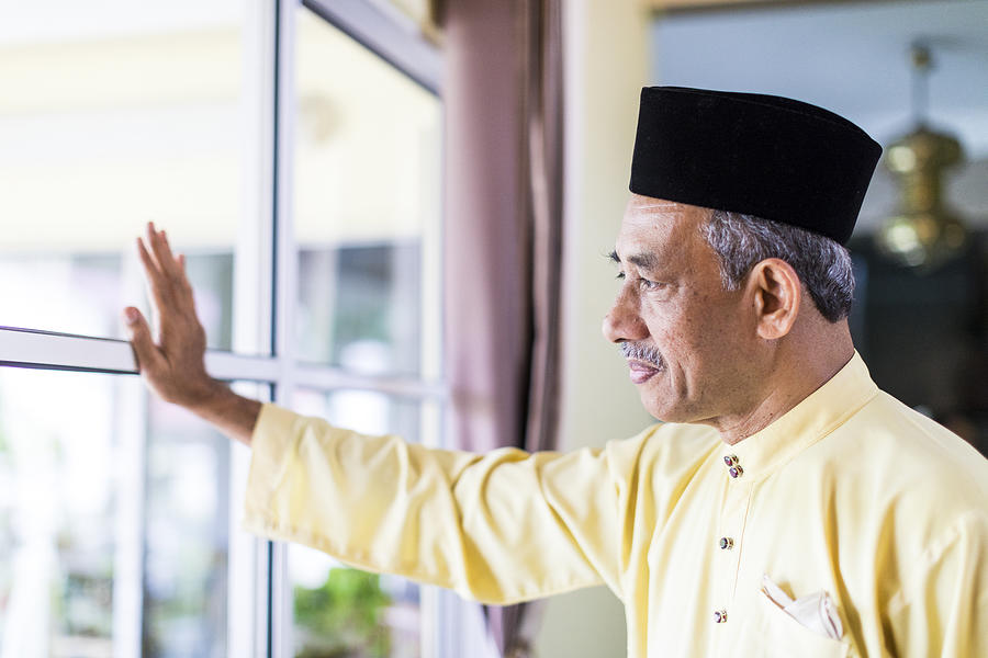 Pensive senior Malaysian Man looking outside window Photograph by GCShutter