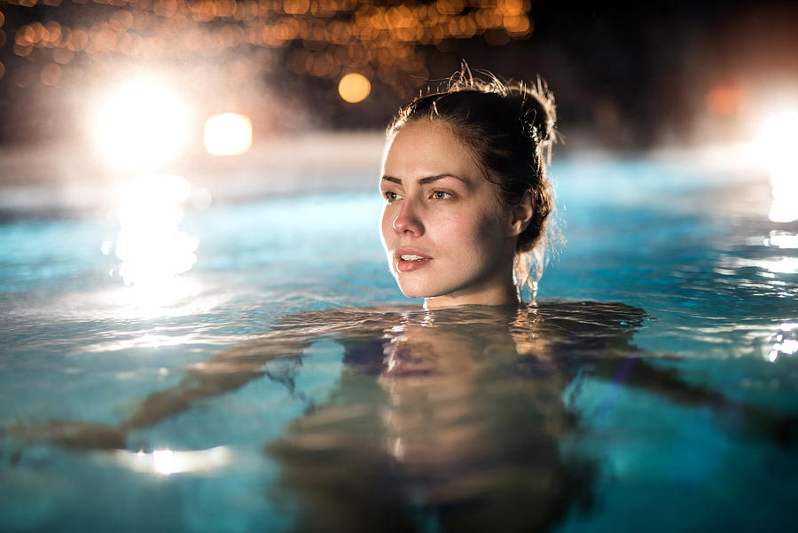 Pensive woman in the heated swimming pool outdoors. Photograph by BraunS