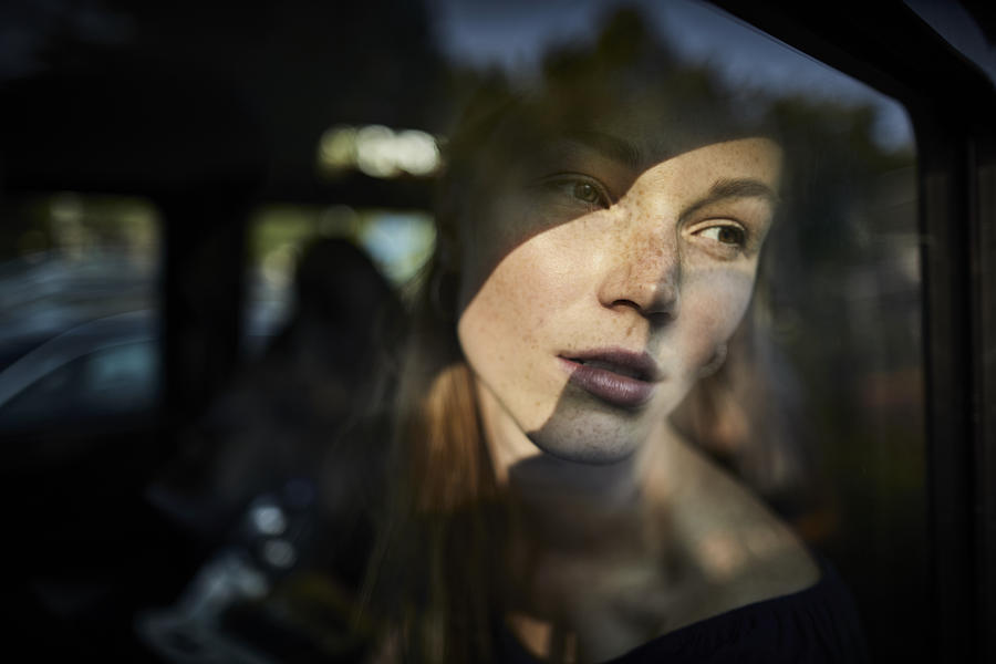 Pensive young woman looking out of car window Photograph by Oliver Rossi