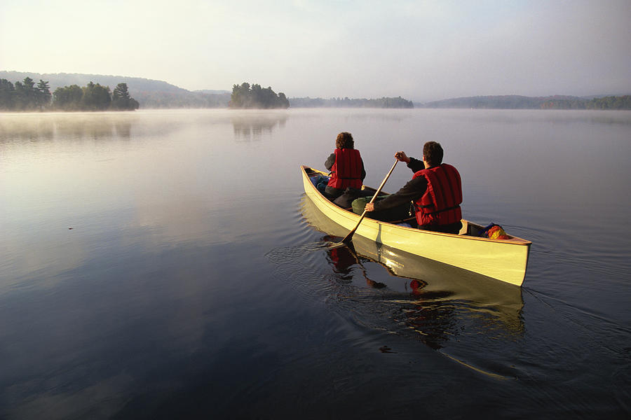 People canoeing on lake Photograph by Comstock Images
