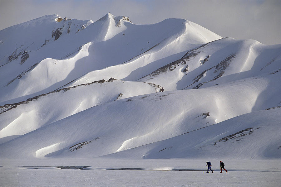 People cross-country skiing by snowy mountain Photograph by Comstock Images
