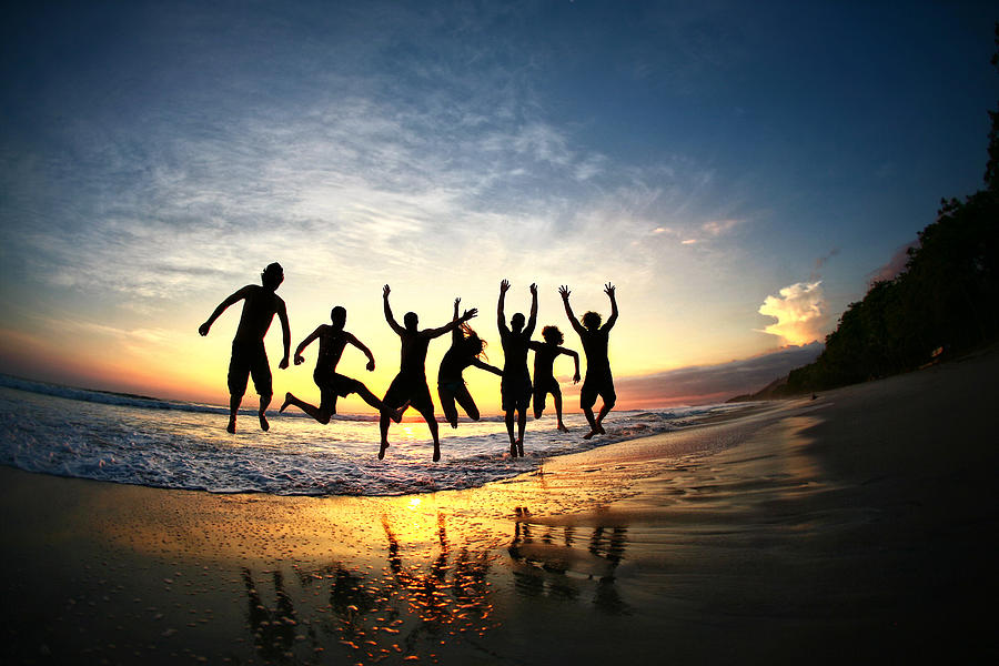 People jumping on beach at sunset in Costa Rica Photograph by Nicole Kucera