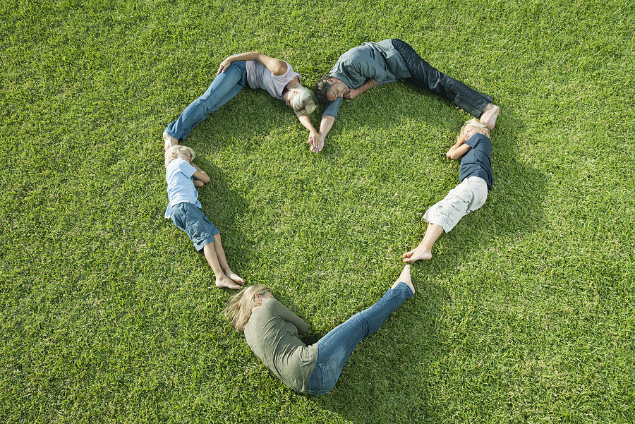 People lying on grass positioned in shape of heart Photograph by PhotoAlto/Milena Boniek