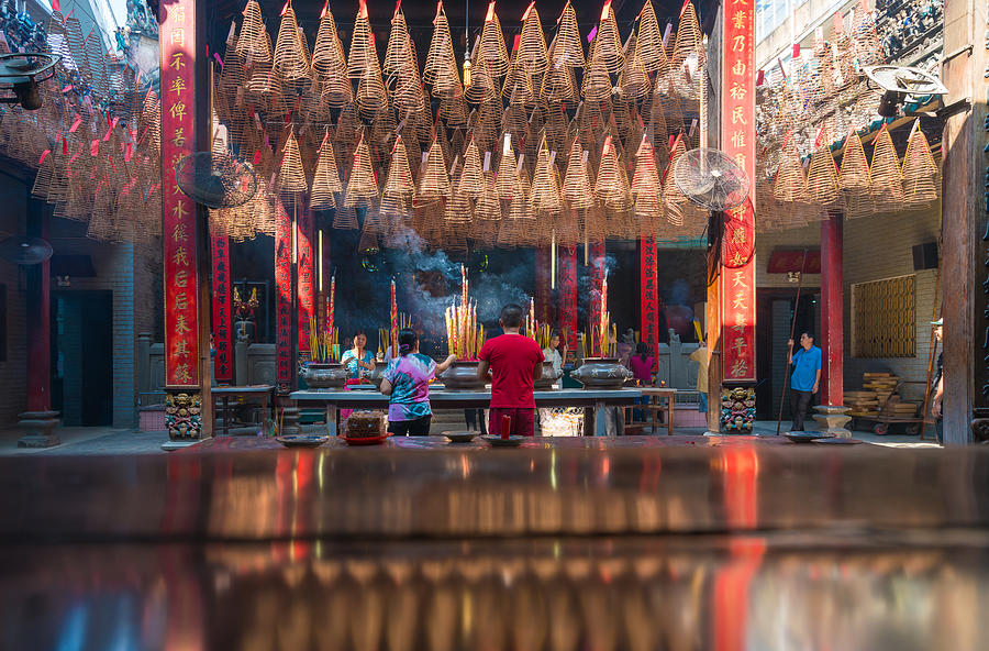 People praying Inside Thien Hau Pagoda Cholon, Ho Chi Minh City. Pagoda for the Cantonese Congregation. Incense burning on the central table with incense prayers above. Photograph by Jethuynh