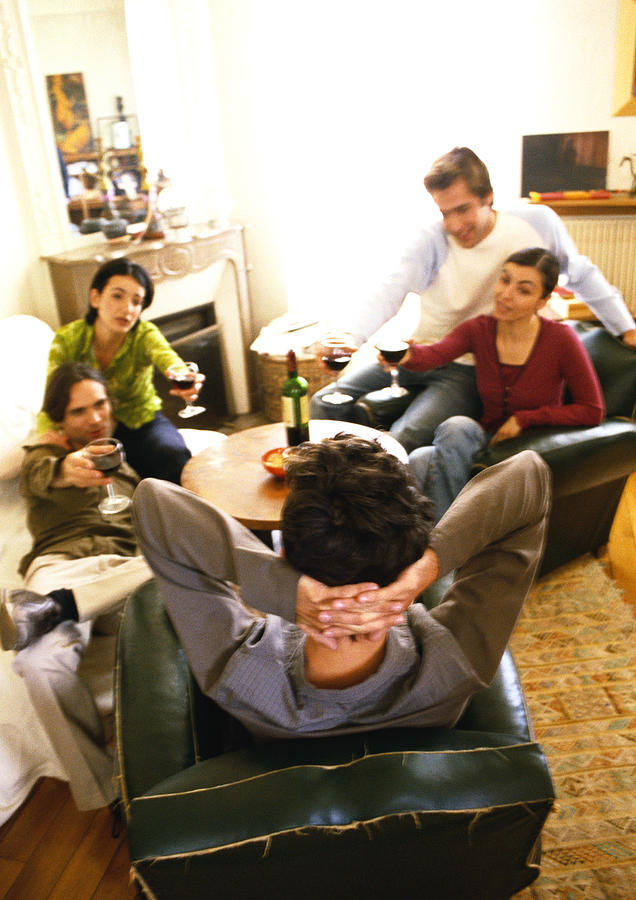 People sitting in living room, drinking wine Photograph by John Dowland