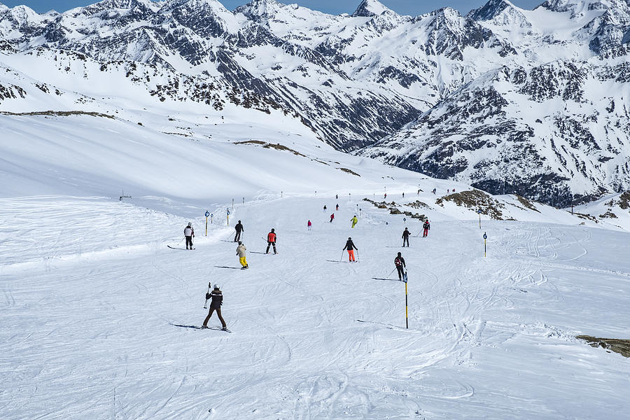 People skiing and snowboarding down a ski slope in the Sölden Ötztal ski area during a sunny winter day Photograph by Sjo