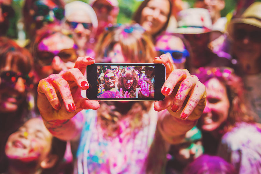 People taking a selfie together in group during a Holi celebration party in the outdoor with happiness expressions and covered with vivid colors. Photograph by Artur Debat