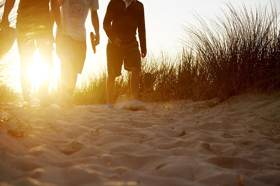 People walking in sandy dunes at sunset Photograph by Chris Tobin