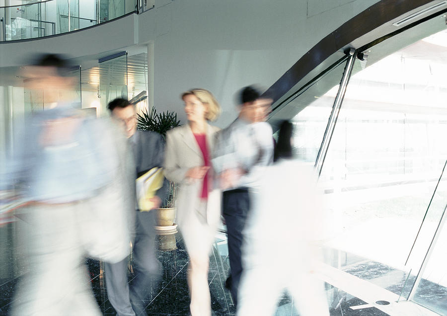 People walking inside office building, blurred Photograph by Eric Audras