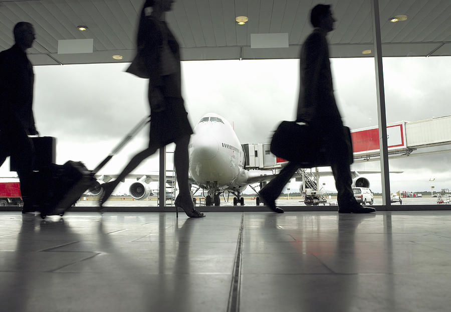 People walking through airport, silhouette (focus on aeroplane) Photograph by John Rowley