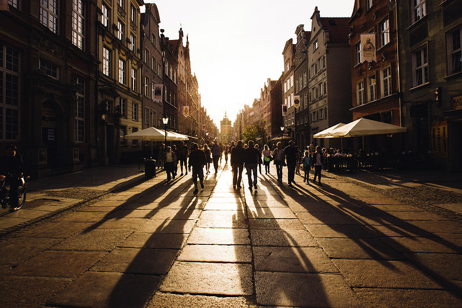 People walking towards the setting sun on an old city street Photograph by Alexander Spatari