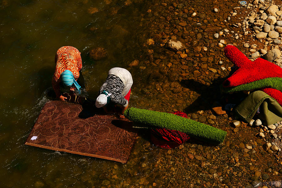 People wash the carpets alongside the river in rural area Photograph by Redtea