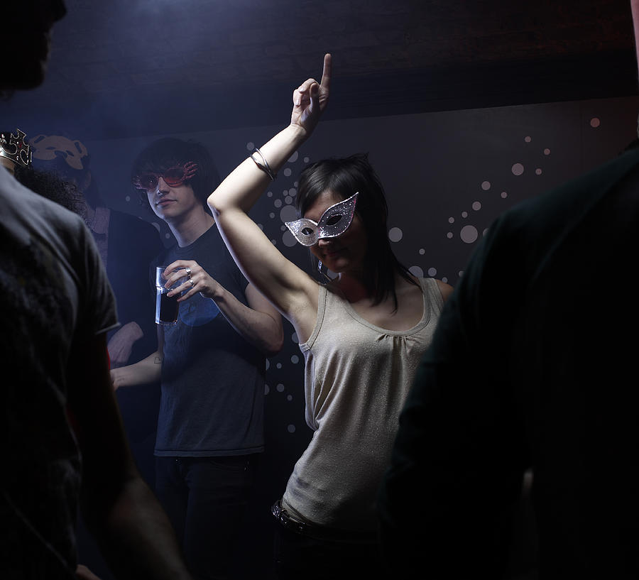 People wearing masks, dancing in night club Photograph by Michael Blann