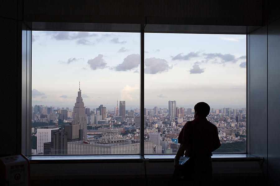 Person looking at city through window Photograph by Image Source