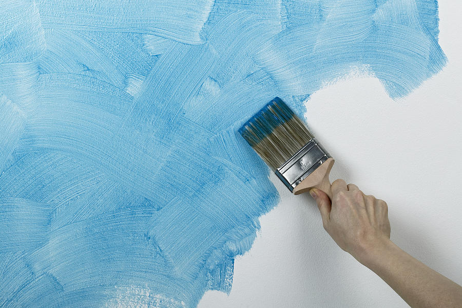 Person painting glaze onto wall with brush Photograph by Dorling Kindersley