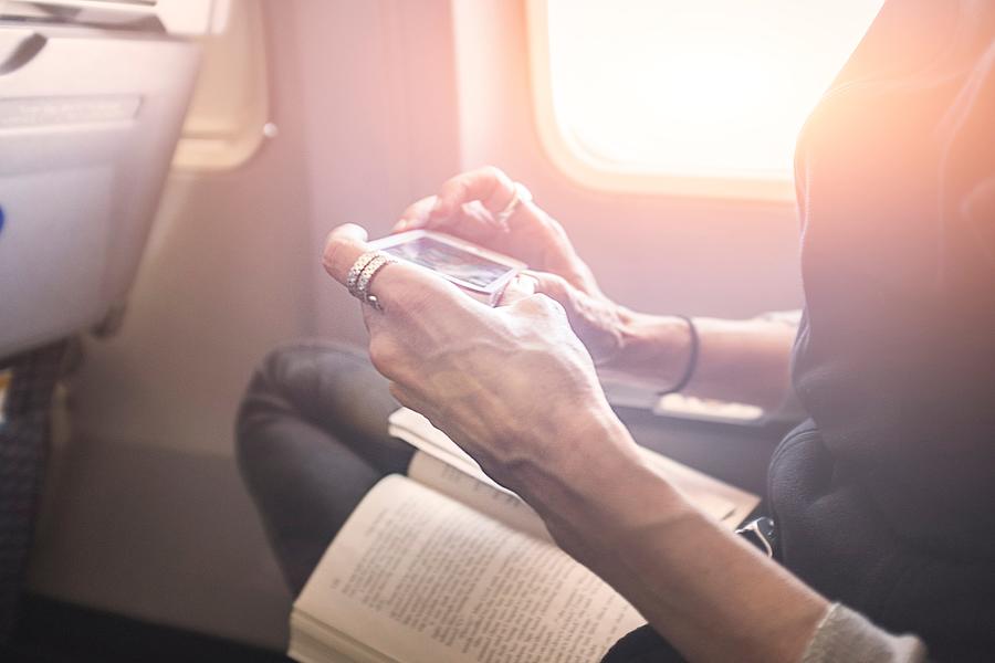 Person playing game on smartphone on board airplane Photograph by Steve Prezant