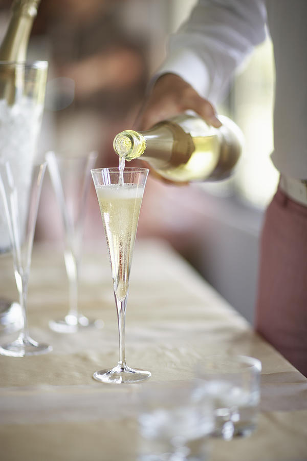 Person pouring champagne into glass, close-up, Mid section Photograph by Maren Caruso