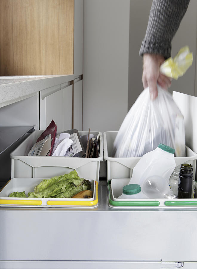 Person removing rubbish bag from waste and recycling drawer Photograph by Image Source