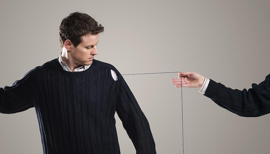 Person unraveling mans sweater, indoors Photograph by Stewart Sutton